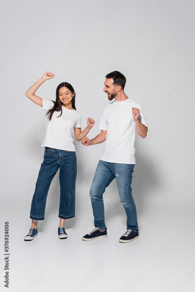 full length view of interracial couple dancing in jeans, white t-shirts and gumshoes on white full length view of interracial couple dancing in jeans, white t-shirts and gumshoes on white