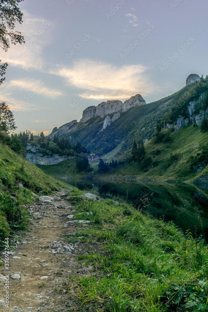 The mountain hut and the Alpstein mountain range reflecting on the Faelensee lake in the Swiss canton of Appenzell at sunrise