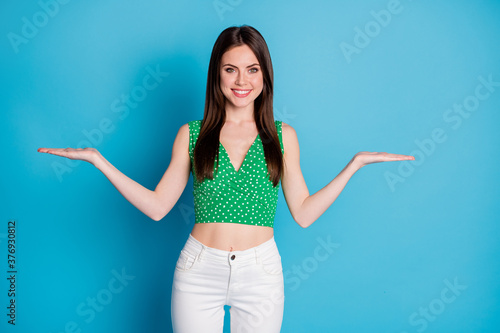 Portrait positive girl promoter hold hand demonstrate advertise ads promotion feedback wear singlet white pants trousers isolated over blue color background