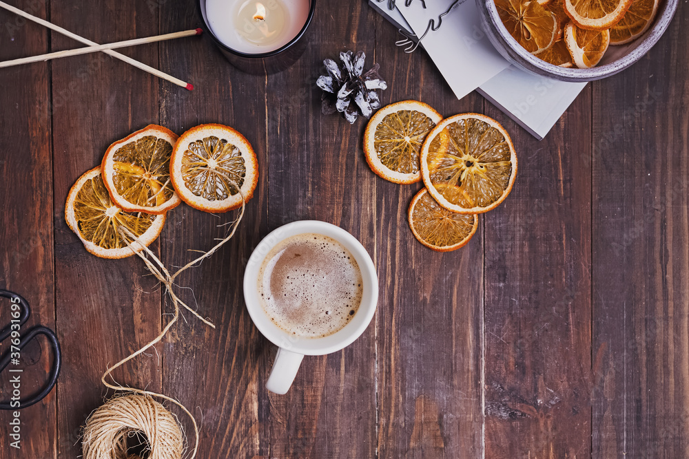 Dry oranges, coffee and candle on wooden table.