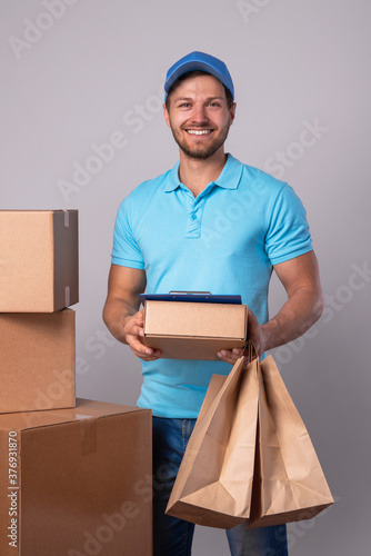 Happy delivery man during work with a packages in a cardboard boxes photo