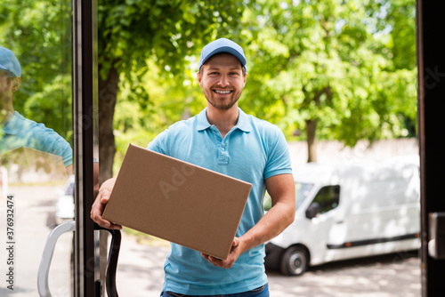  Smiling courier bring a package in the cardboard box to your house