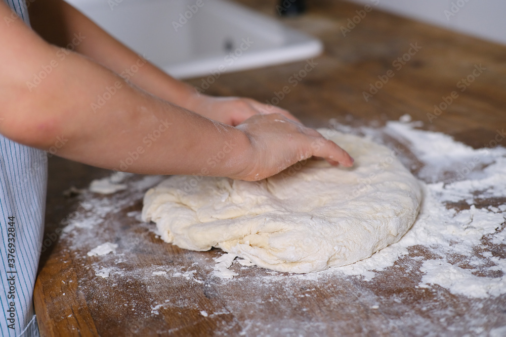 dough in flour kneading children's hands, one kid, child helps parents in kitchen, concept of a happy childhood, household help, homework, food preparation dough in flour kneading children's hands, one kid, child helps parents in kitchen, concept of a happy childhood, household help, homework, food preparation