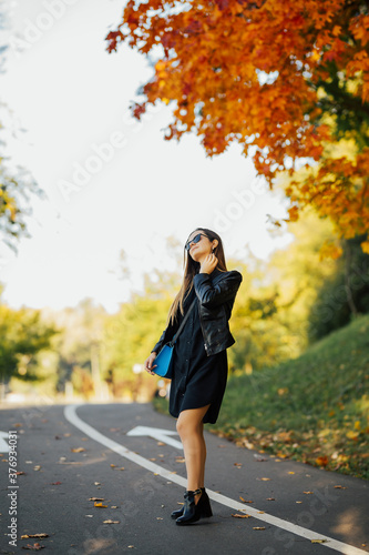 Girl with a sweet smile posing in a warm autumn on the road. Autumn background.