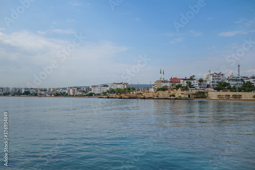 Panoramic view onto shoreline of resort city Kizkalesi, Turkey. It's included beach, hotels, mosques, restored ancient stone fortifications etc. It's typical view on Turkish town near Mediterranean © Poliorketes
