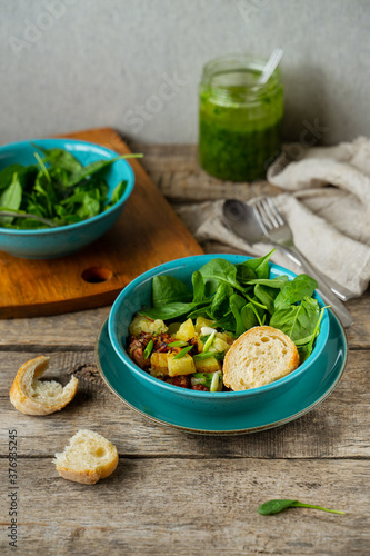 Potato, bacon and sausage salad with fresh spinach, country style, closeup view
