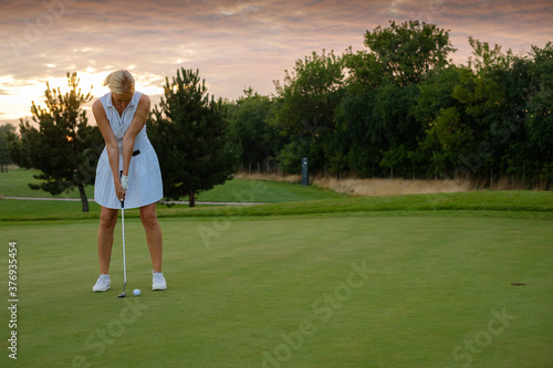 Lady Focused On Hitting Ball Into Golf Hole .