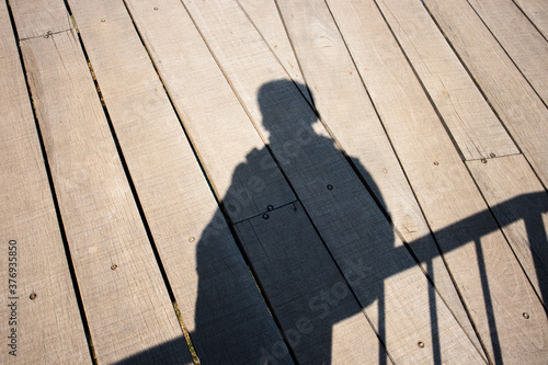 shadow of man on wooden bridge