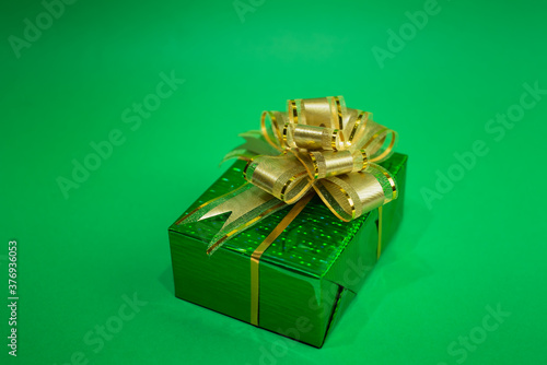 Surprise gift of green color with a bow on a green background