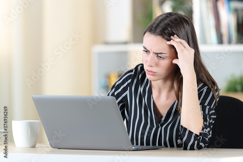 Worried woman checking laptop at home