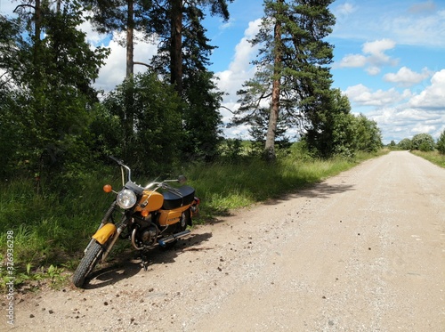 Old Russian yellow motorcycle motorbike pine trees. gravel road. countryside. photo