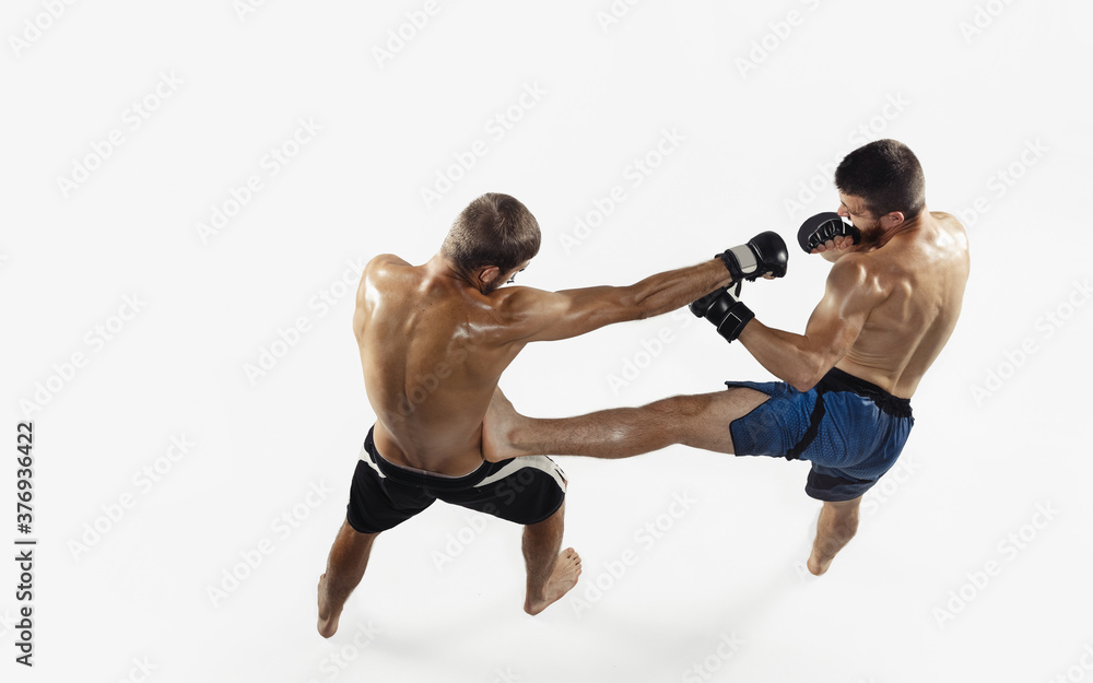 Two professional MMA fighters boxing isolated on white studio background. Top view of couple of muscular athletes. Sport, healthy lifestyle, competition, dynamic and motion, action concept. Copyspace. Two professional MMA fighters boxing isolated on white studio background. Top view of couple of muscular athletes. Sport, healthy lifestyle, competition, dynamic and motion, action concept. Copyspace.