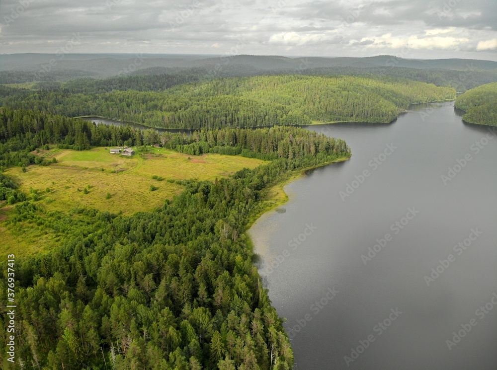 Lake in forest with cloudy sky. Aerial view Russian Karelia. lonely farm house