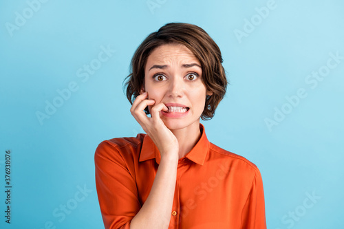 Oh no I failed again. Closeup photo of sad terrified lady horrified facial expression made big mistake feel guilty bite lips fingers wear orange shirt isolated blue color background