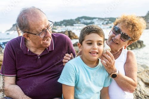 Grandparents and grandson playing with a shell on the beach
