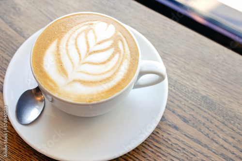 Close-up of hot cappuccino coffee dressing with leave shape of latte art