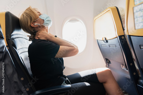 Woman wearing prevention mask during a flight inside an airplane