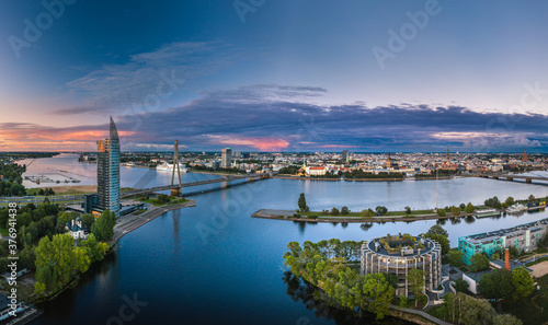 Obraz na płótnie Riga city panorama with colorful sunset in the sky. Modern architecture meets old town. Picturesque view over riverside. w salonie