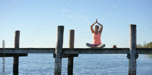 junge sportliche Frau macht Yoga am See