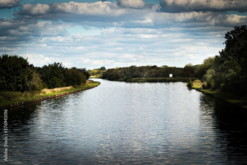 pleasure boats on the canal, calm day with clear reflection on the water, trees and blue sky