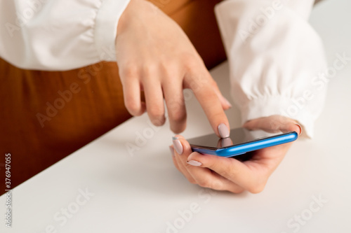 girl with a smartphone at the table does shopping via mobile screen