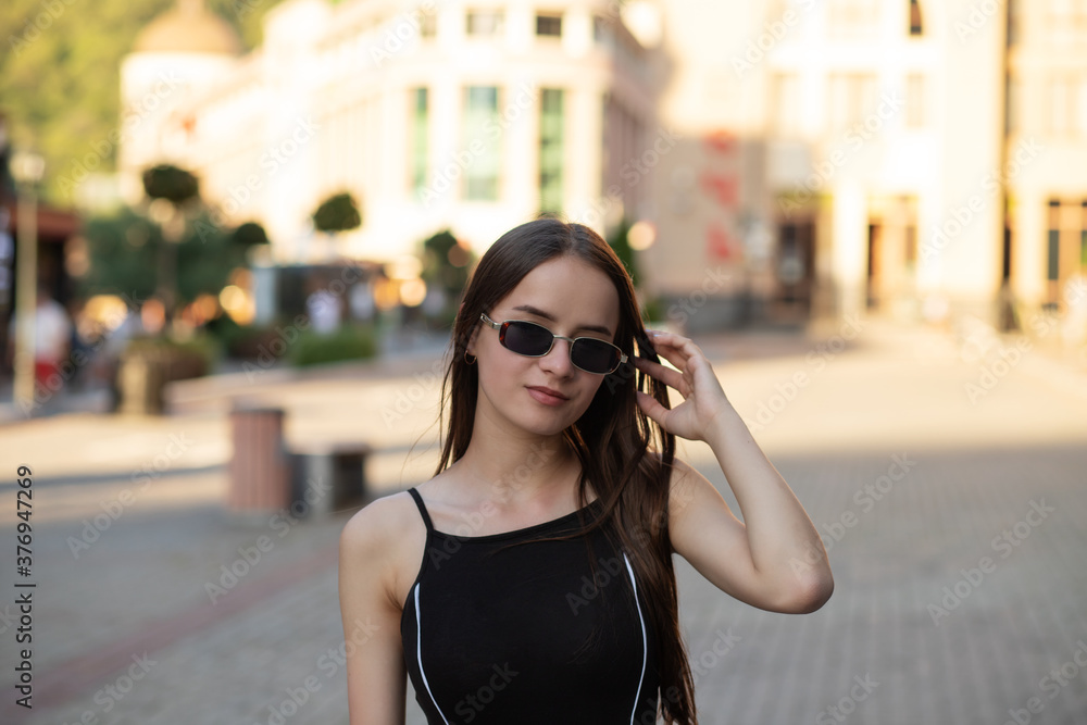 Young girl in sunglasses on a city street in summer