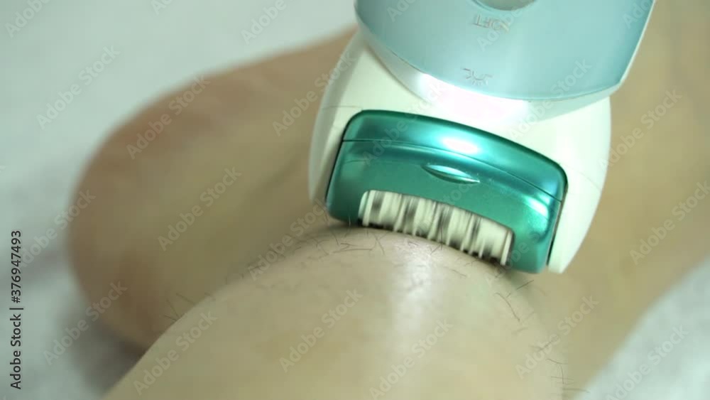 Electric epilator pulls out the hairs in closeup. Slow motion. Woman