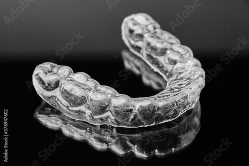 Invisible transparent dental removable braces on the black background. Orthodontic appliance for dental correction. Aligners for teeth straightening.