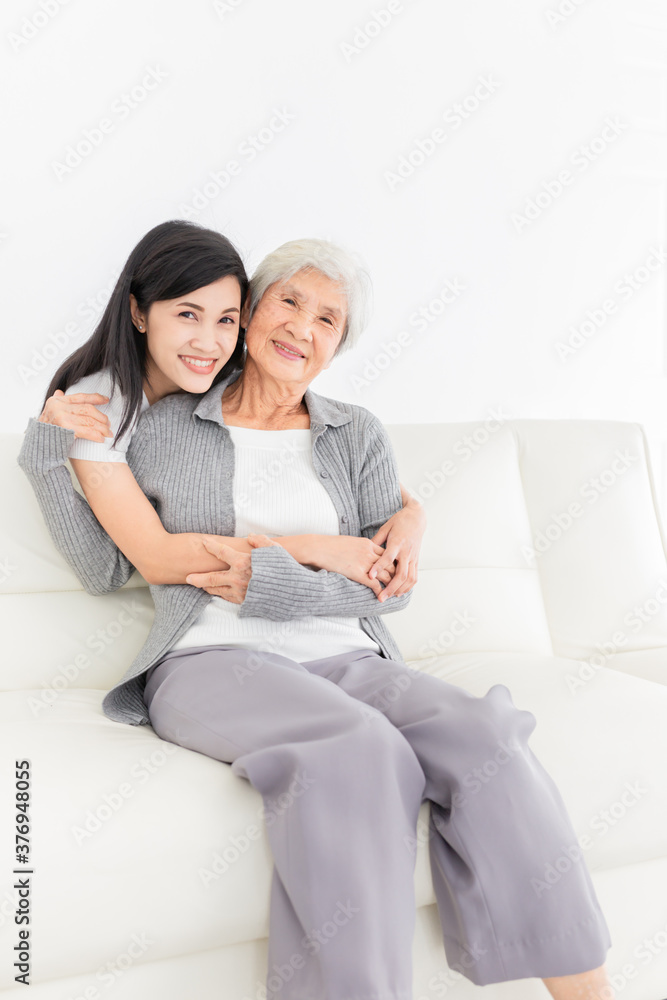 young Asian female hug old female in home, they feeling happy and smile, they sitting on sofa, mother's day, happiness elderly in family time young Asian female hug old female in home, they feeling happy and smile, they sitting on sofa, mother's day, happiness elderly in family time