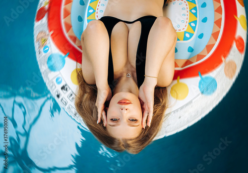 Sexy blonde with a beautiful figure lying in the pool on an air mattress. Vacation concept. © Yuliia