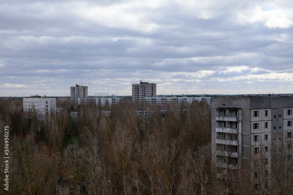Abandoned panel houses among leafless trees in Pripyat. Beautiful cloudy sky over the city. Post-Soviet architecture.
