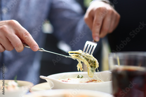 Fototapeta Naklejka Na Ścianę i Meble -  Bistro visitor sitting at table holding fork and knife with piece of bolognese. Lunch menu in restaurants and cafes concept