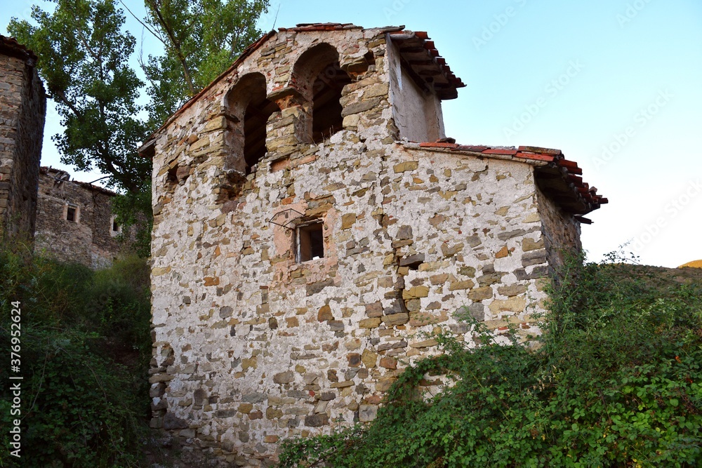Ruins of the church of Santa Ana in Valtrujal with lush vegetation around.