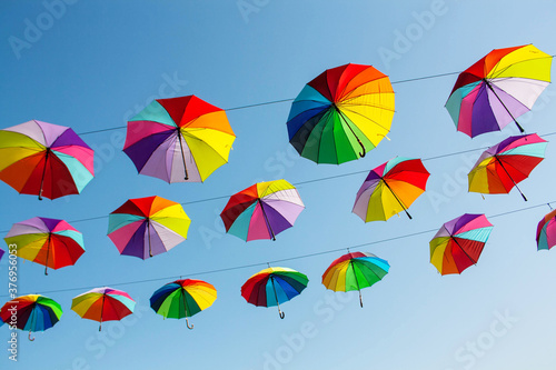 Multi-colored umbrellas on the blue sky background. Colorful autumn concept