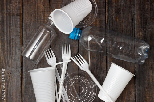 Plastic dishes, bottles, glasses on a white table. Planet pollution