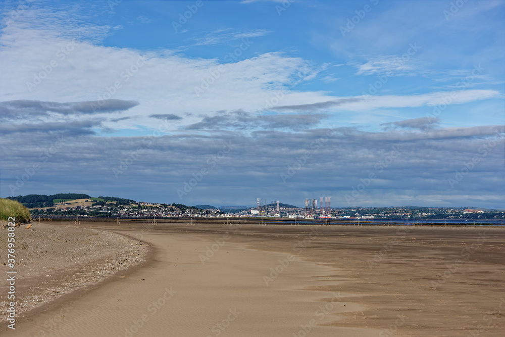 The built up area of the City of Dundee Port with Oil Rigs in for maintenance, and the small town of Tayport on the other side of the Estuary.