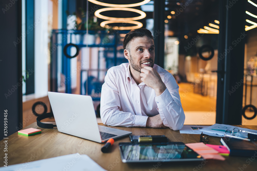 Fototapeta premium Thoughtful young man with laptop in contemporary workspace