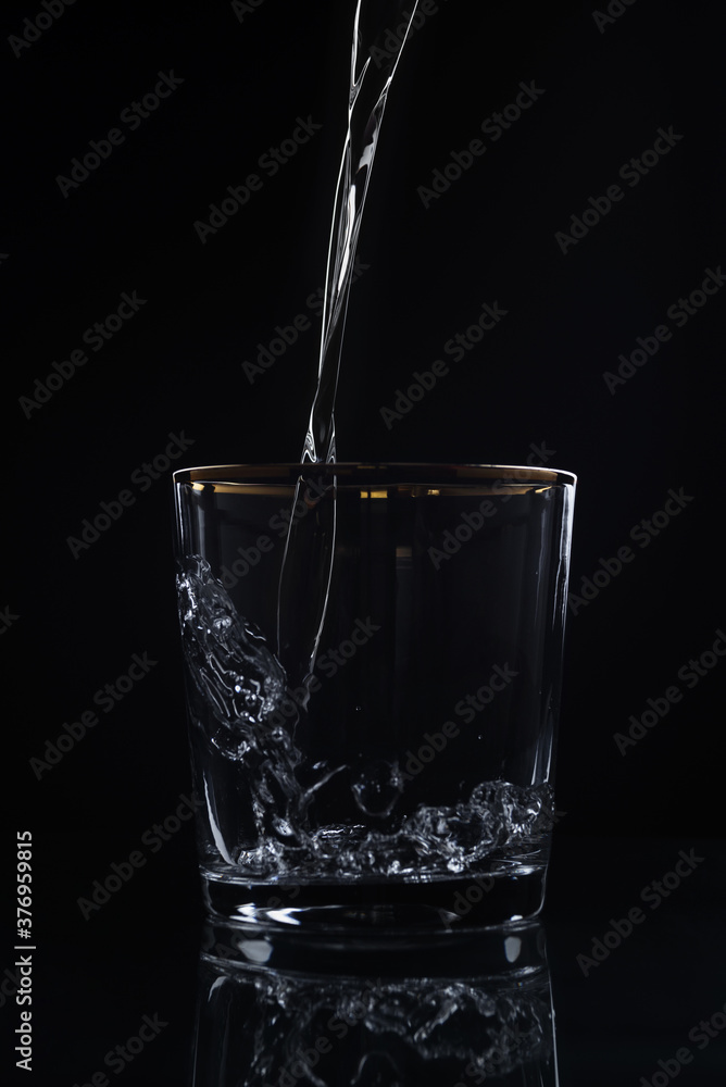 Water pouring into glass on dark background Water pouring into glass on dark background