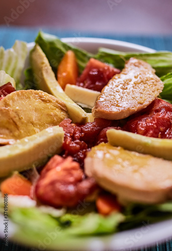 Ensalada de lechuga con tomates, pollo, palta, queso, zanahoria y queso. Vinagreta dulce. Fondo de textura turquesa photo