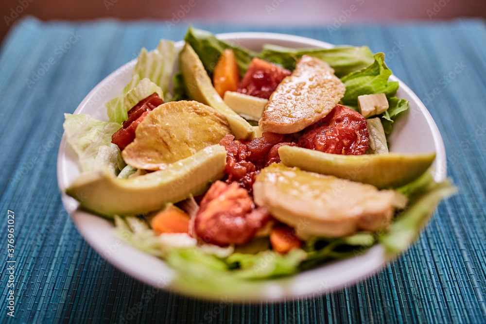 Ensalada de lechuga con tomates, pollo, palta, queso, zanahoria y queso. Vinagreta dulce. Fondo de textura turquesa Ensalada de lechuga con tomates, pollo, palta, queso, zanahoria y queso. Vinagreta dulce. Fondo de textura turquesa