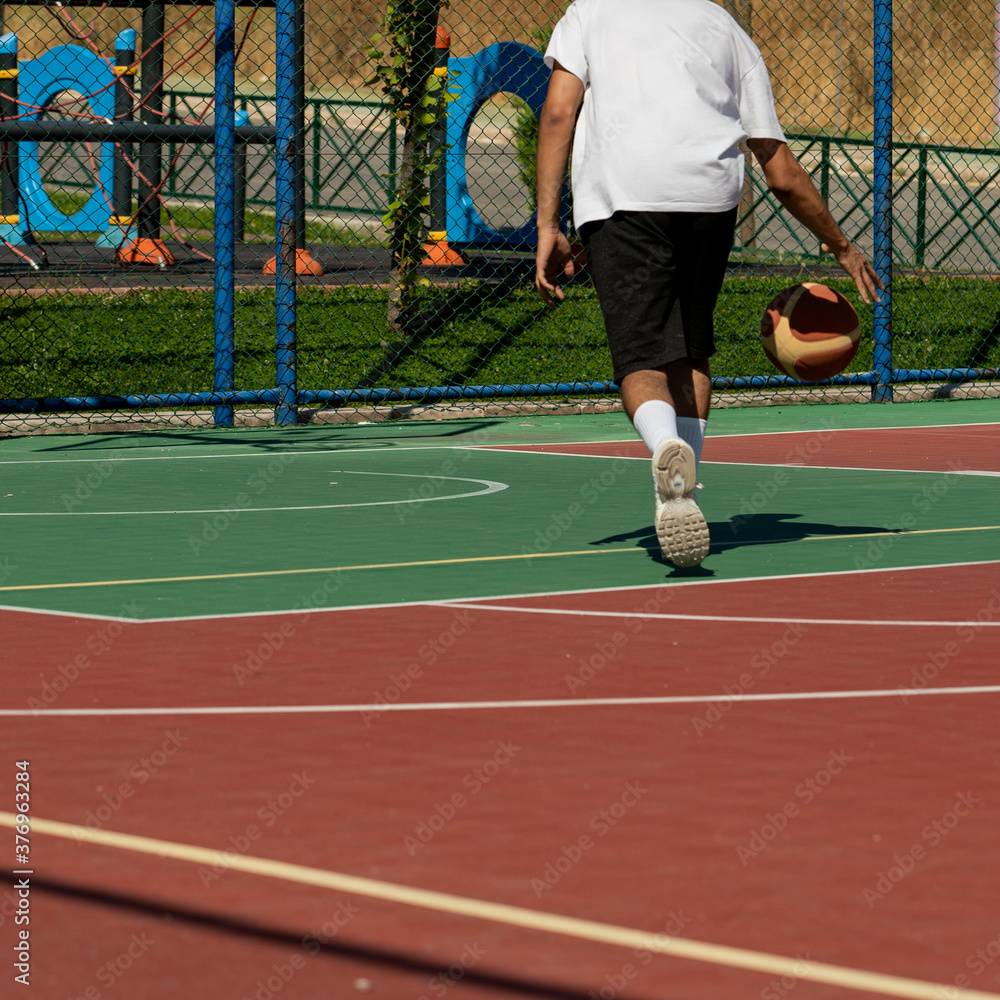 Young man on basketball court dribbling with ball