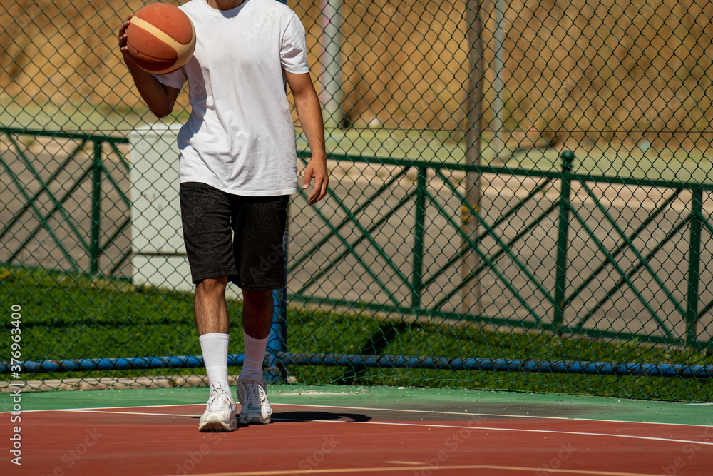 Obraz premium Young man on basketball court dribbling with ball