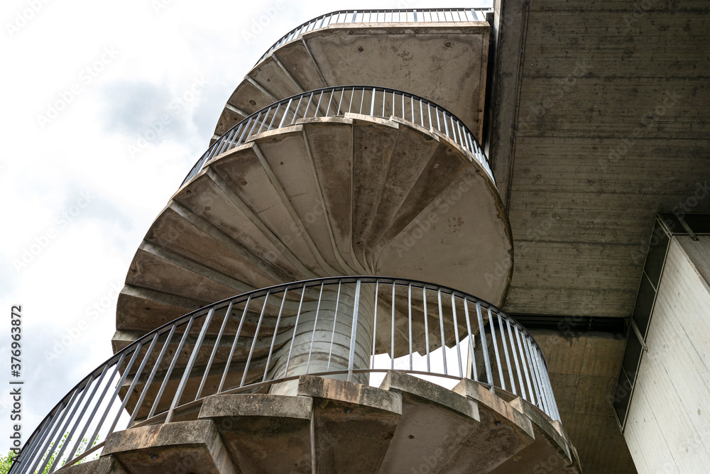 Fototapeta premium Concrete spiral staircase with metal handrails for pedestrian traffic to the bridge.