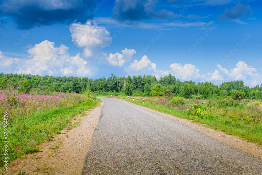 A road, a blooming field in central Russia and incredibly beautiful clouds in the sky. Pskov region A road, a blooming field in central Russia and incredibly beautiful clouds in the sky. Pskov region