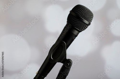 micrófono de color negro en un pie con fondo blanco con luces blancas