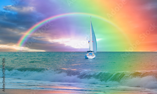 Yacht sailing in open sea at stormy day - Anchored sailing yacht on calm sea with tropical storm and double sided rainbow in the background