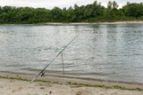 the fishing rod stands at a stop near a picturesque river.  Waiting for fish catch. Relaxing and soothing stay