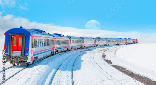 Red diesel train (East express) in motion at the snow covered railway platform with full moon - The train connecting Ankara to Kars - Turkey 