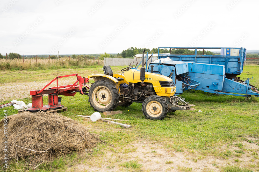 Fototapeta premium yellow tractor with red bucket stands on the grass