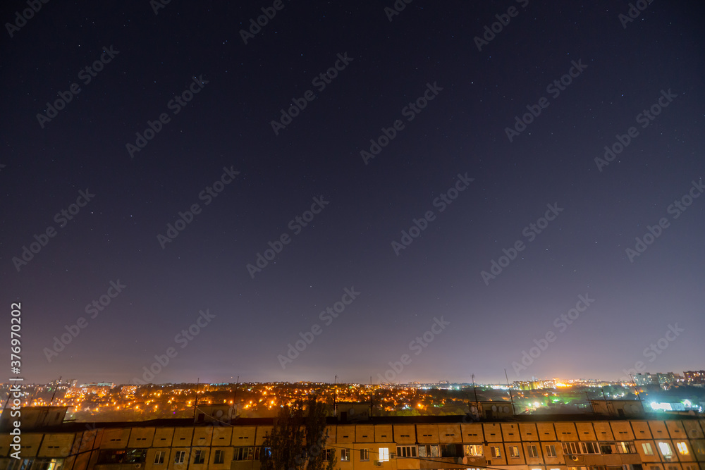 Fototapeta premium Night starry cityscape with a lot of stars and constellations.